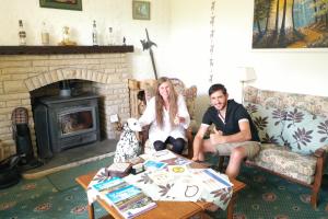 a man and woman sitting in a living room with a dog at Garden Park Guest House in Grantown on Spey