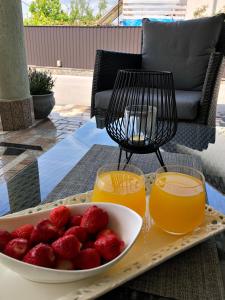 a plate of strawberries on a table with two glasses of orange juice at Sobe Darko Cindrić in Karlovac
