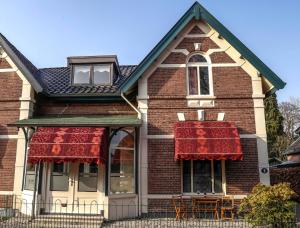 uma casa com dois tapetes vermelhos nas janelas em De Grift em Apeldoorn