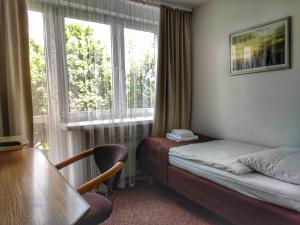 Cette chambre comprend un lit, une table et une fenêtre. dans l'établissement Hotel Logos, à Varsovie