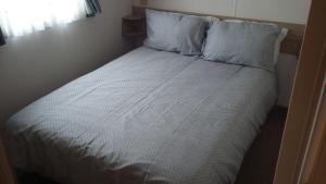 Una cama con sábanas blancas y almohadas en un dormitorio en KINGDOM HOLIDAY PARK, en Haverigg