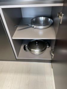 a metal counter with a frying pan in a cabinet at Gangneung hi ocean gyeongpo a203 in Gangneung