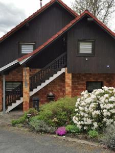 a house with a black roof and some flowers at Zur langen Heide in Hildburghausen