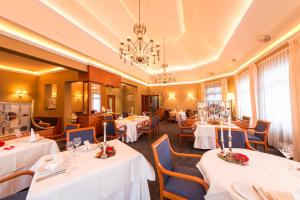 a restaurant with white tables and chairs and a chandelier at Schloß-Hotel Petry in Treis-Karden