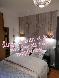Ô bord de L' eau في لو تريبور: غرفة نوم مع سرير مع علامة نيون عليه