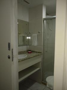 a bathroom with a sink and a shower with a mirror at Flat na Praia do Farol da Barra in Salvador