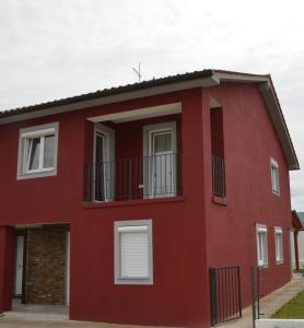 een rood huis met witte ramen en een balkon bij Casa Lucia in Koper