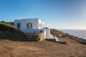 een wit huis op een heuvel naast de oceaan bij Petala House in Cherronisos