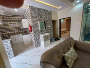 een woonkamer met een bank en een bakstenen muur bij شاليهات سويت هوم الدرب الكدره in Ad Darb