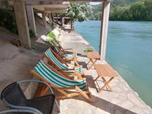 a group of chairs and tables next to a river at Apartmani ODMOR NA DRINI in Ljubovija