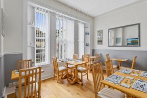Un comedor con mesas y sillas y ventanas. en Westbrook Guesthouse, en Torquay