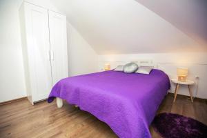 1 dormitorio con 1 cama de color púrpura y 2 lámparas en LURIA apartmens - self check in apartments en Čakovec
