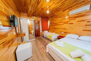 a bedroom with two beds in a wooden wall at Ikiz Pension Bungalow in Cıralı