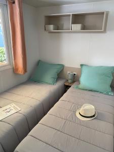 a room with two beds with a hat on it at Mobil Home 3 chambres climatisé tout équipé in Valras-Plage