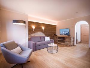 a living room with a purple couch and a tv at Appartements Schedererhaus in Going am Wilden Kaiser