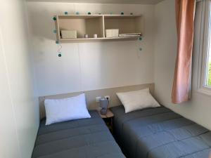 two blue beds in a room with a window at Mobil Home 3 chambres climatisé tout équipé in Valras-Plage