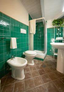 un bagno piastrellato verde con servizi igienici e lavandino di Da Palù a Castellabate