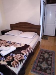 a bedroom with a large bed with white pillows and a rug at Maya Guest House in Sighnaghi