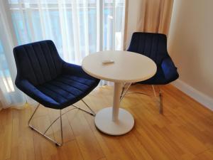 2 blaue Stühle, ein weißer Tisch, ein Tisch und Stühle in der Unterkunft Subtropik Apartments in Batumi in Batumi