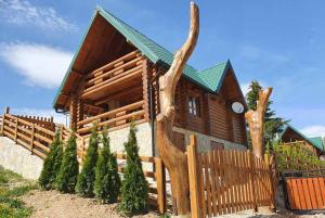 a log cabin with a fence and a tree trunk at Zlatar Luxury Chalet - TRACE OF NATURE 2214 in Nova Varoš