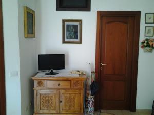 a television sitting on top of a wooden cabinet next to a door at Rubens in Alghero