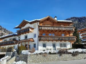 Casa grande con balcones de madera en una pared de piedra. en Luxury Apartment Daema en Selva di Val Gardena
