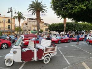 un carro de golf estacionado en un estacionamiento con coches en Villa glori, en Marina di Gioiosa Ionica