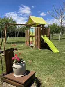 um parque infantil com um vaso de flores sobre uma mesa e uma estrutura de brincar em La Massonnière Gîte et chambres d'hôtes em Mondion