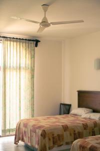 a bedroom with two beds and a ceiling fan at Hotel Caracol Plaza in Puerto Escondido