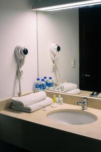 a bathroom with a sink and a large mirror at Hotel Caracol Plaza in Puerto Escondido