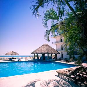 a swimming pool with palm trees and a hotel at Hotel Caracol Plaza in Puerto Escondido