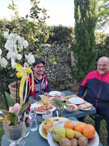 dos hombres sentados en una mesa con comida. en B&B Il Giardino Etrusco en Saturnia