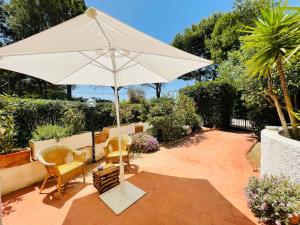 - un parasol blanc assis sur une terrasse avec des chaises dans l'établissement La maison sul mare, à San Vito Lo Capo