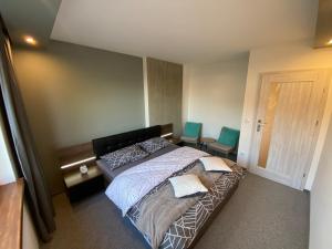 a bedroom with a large bed with two blue chairs at Apartamenty Pod Jesionem in Zator +30 photos