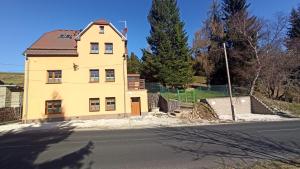 Vila Kokrhačka في لويكنا بود كلينوفسيم: منزل أصفر على جانب الطريق