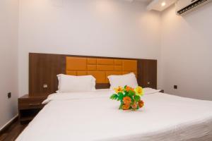 ال متعب سويتس الإزدهار 2 في الرياض: غرفة نوم مع سرير مع إناء من الزهور عليه