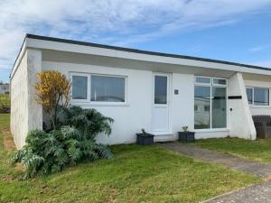 a white house with a green yard at Chalet 23 Widemouth Bay in Bude