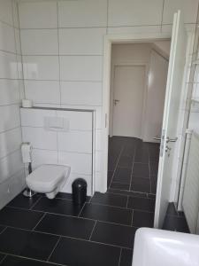 a bathroom with a toilet and a black tile floor at Yellow House in Osnabrück