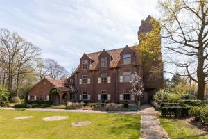 an old brick house with a tower on a lawn at Hotel Torenhof in Sint-Martens-Latem