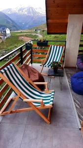dwa krzesła ogrodowe siedzące na ganku z górami w tle w obiekcie Cottage in Gudauri w mieście Gudauri