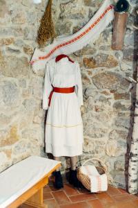 une femme en robe blanche debout à côté d'un mur de pierre dans l'établissement Kmečka hiša Bahor, à Črnomelj