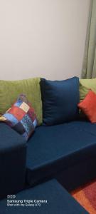 a blue couch with colorful pillows on it at Annettes Place in Naivasha