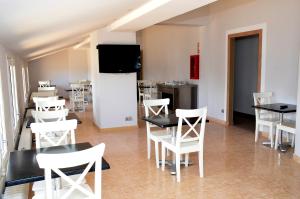 une salle à manger avec des tables et des chaises blanches et une télévision dans l'établissement Hotel Terranova, au Pas de la Case