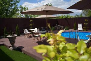 un patio con mesa, sombrilla y piscina en Pensiunea Casa Zece, en Turda