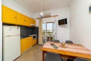 a kitchen with a table and a white refrigerator at La Stella Apartments in Amoudara Herakliou