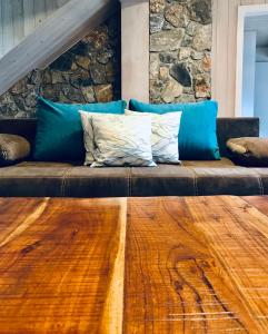 a brown couch with blue pillows and a stone wall at Chata pod Obřím hradem in Nicov