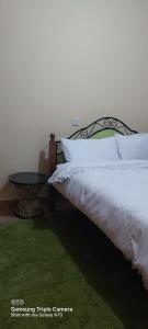 a bedroom with a bed with white pillows and a table at Annettes Place in Naivasha
