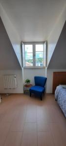 a attic room with a blue chair and a bed at CasAzulApartments in Sintra