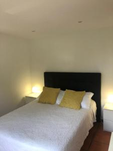 a bedroom with a white bed with two yellow pillows at Angelas - Casa da Galega in Vila Praia de Âncora