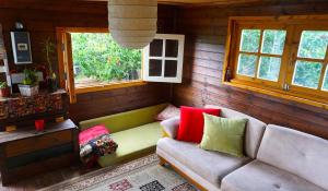 a living room with a couch and two windows at Cantina Cabin's - Think Nature in Mas'ade